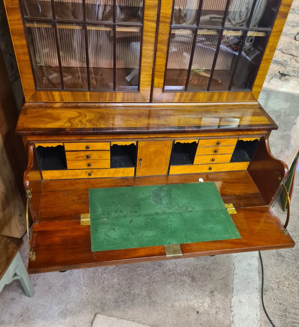A nineteenth-century mahogany secretaire bookcase featuring an upper cabinet with twin astragal glazed doors above a lower chest with three drawer fronts set on turned feet. View III