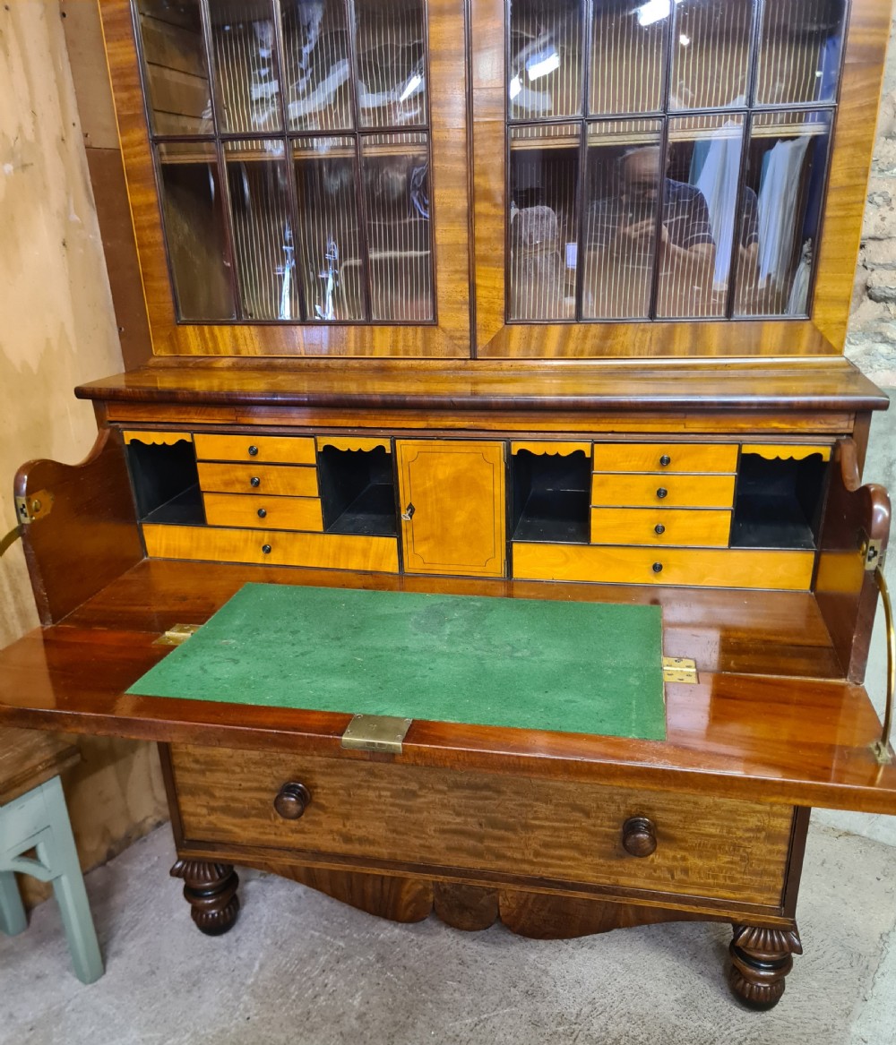 A nineteenth-century mahogany secretaire bookcase featuring an upper cabinet with twin astragal glazed doors above a lower chest with three drawer fronts set on turned feet. View VI