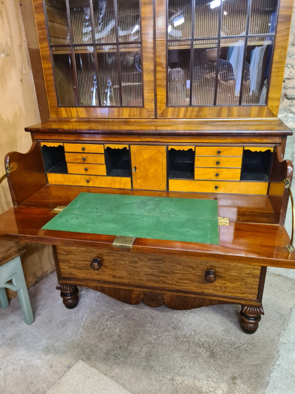 A nineteenth-century mahogany secretaire bookcase featuring an upper cabinet with twin astragal glazed doors above a lower chest with three drawer fronts set on turned feet. View IX