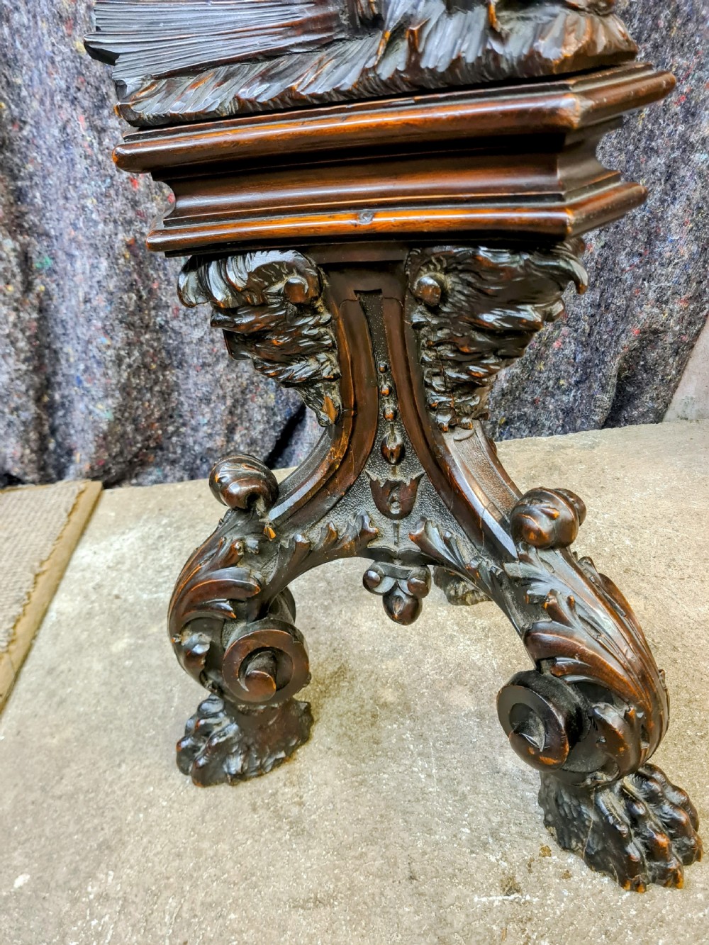 A 19th-century carved dark lime wood sculpture of a putto holding a shell basin aloft, standing on an ornate scroll-carved pedestal. View XI