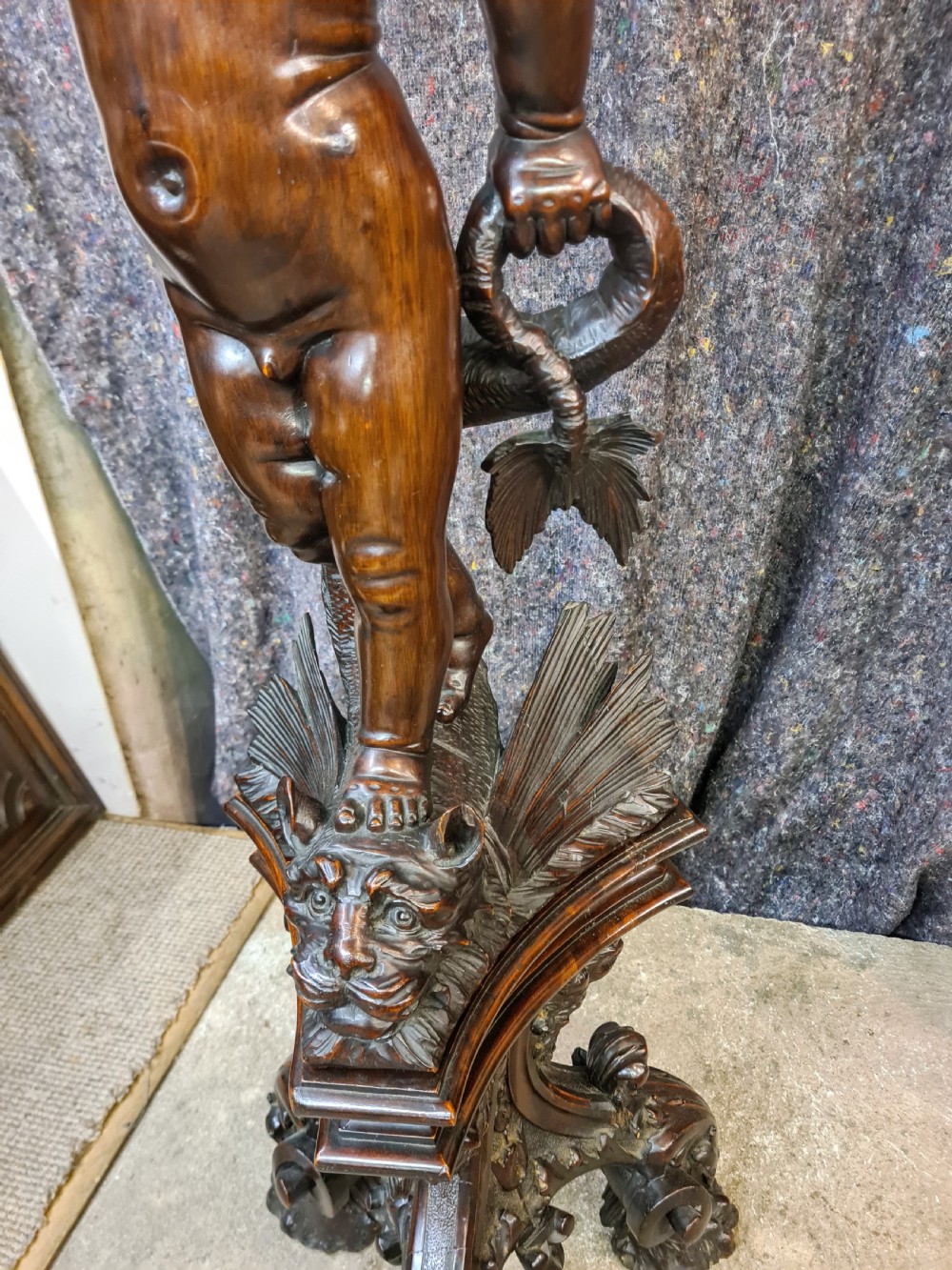 A 19th-century carved dark lime wood sculpture of a putto holding a shell basin aloft, standing on an ornate scroll-carved pedestal. View XII