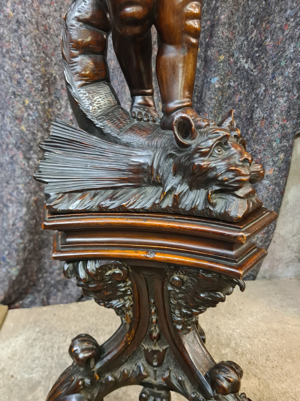 A 19th-century carved dark lime wood sculpture of a putto holding a shell basin aloft, standing on an ornate scroll-carved pedestal. View XIII