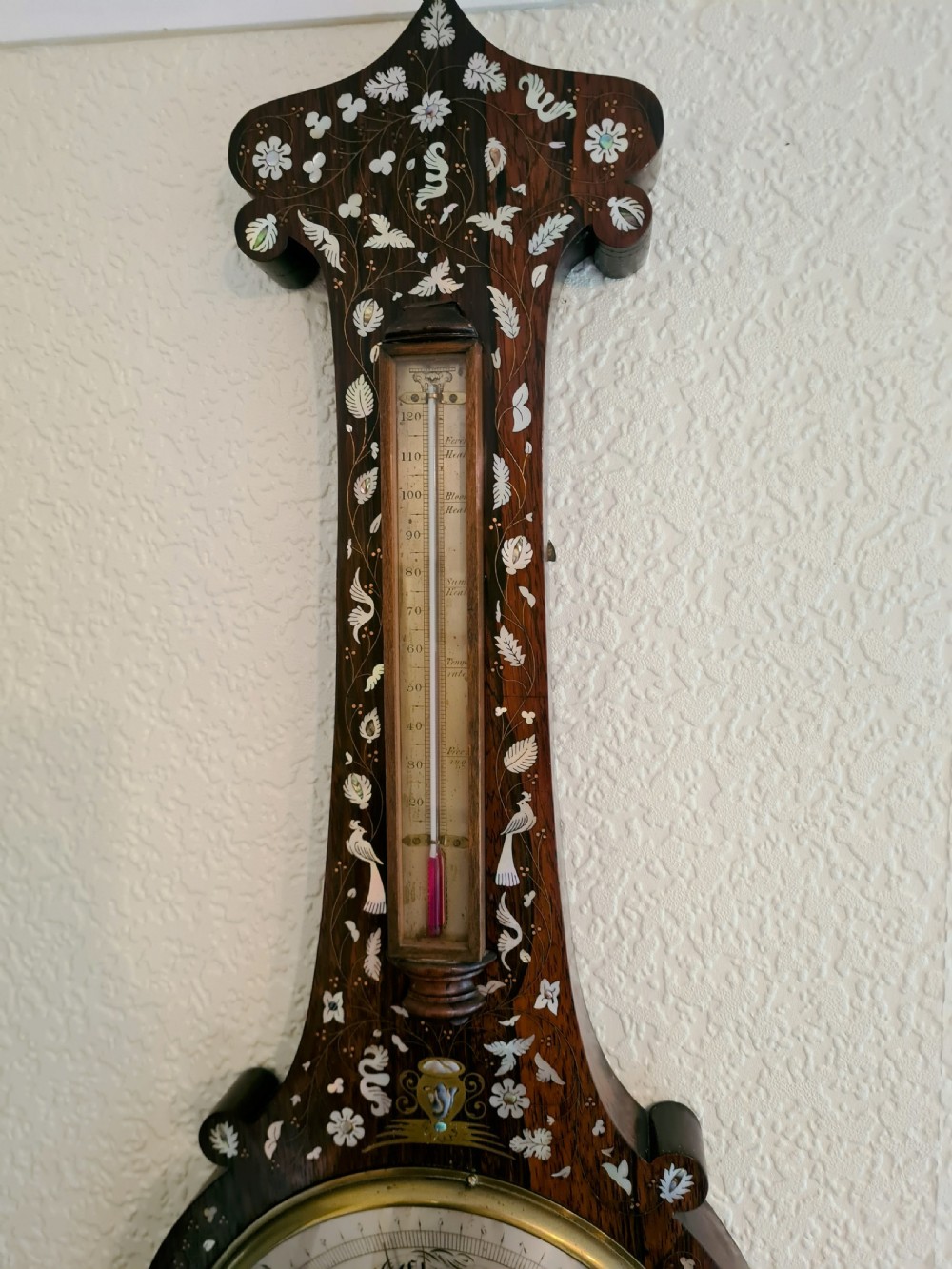 A 19th-century dark rosewood banjo barometer featuring intricate mother-of-pearl floral and bird inlays, an integrated thermometer, and a central round silvered dial. View VII