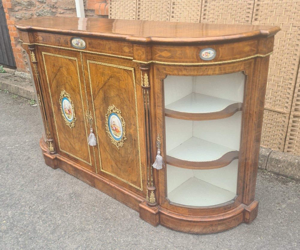 A Victorian burr walnut credenza with central timber doors framed in ormolu, featuring oval Sevres-style porcelain plaques and curved glass display cabinets on each side. View IV
