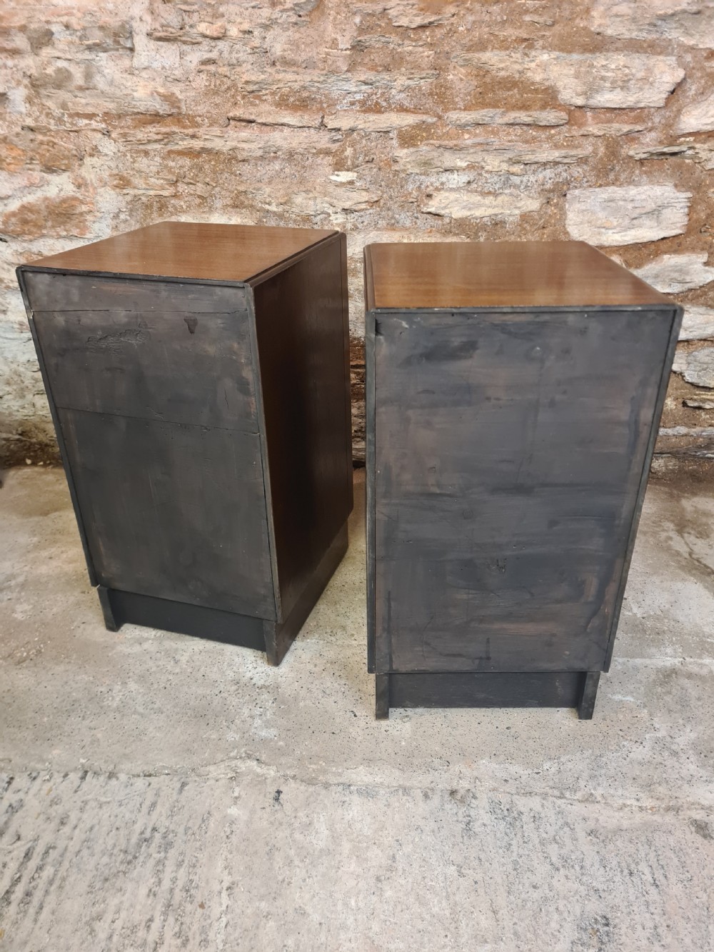 A pair of mahogany Art Deco bedside cabinets featuring three drawers each with round brass knobs on a solid plinth base. View VII
