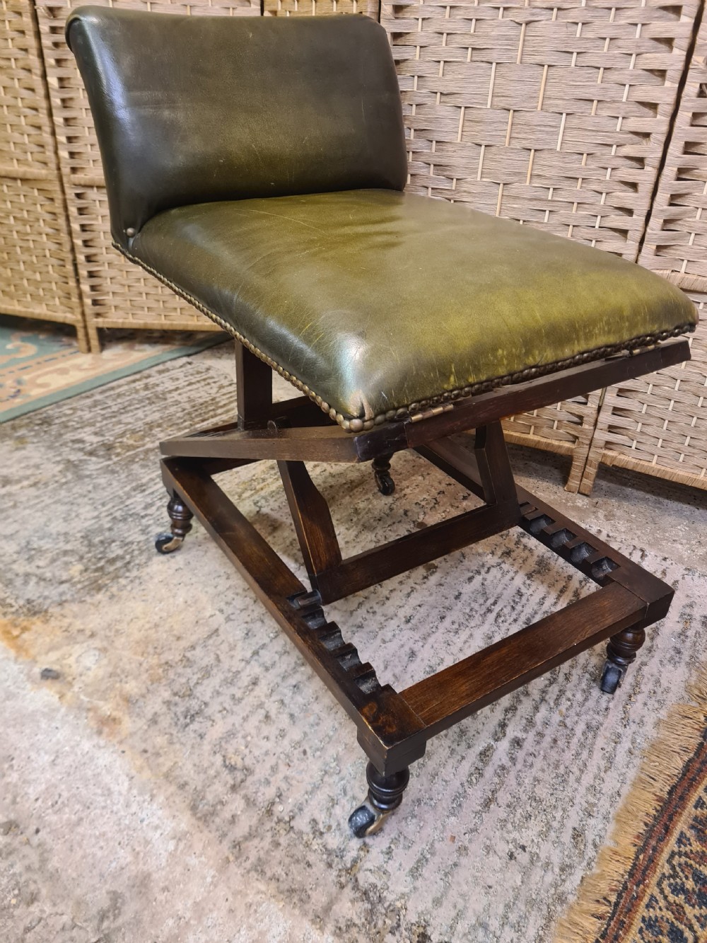 An Edwardian metamorphic gout stool crafted from dark mahogany with green leather upholstery, brass stud detailing, and a notched ratchet adjustment mechanism. View II