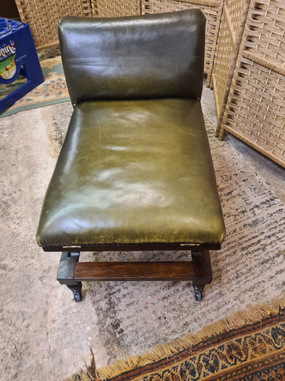 An Edwardian metamorphic gout stool crafted from dark mahogany with green leather upholstery, brass stud detailing, and a notched ratchet adjustment mechanism. View IV