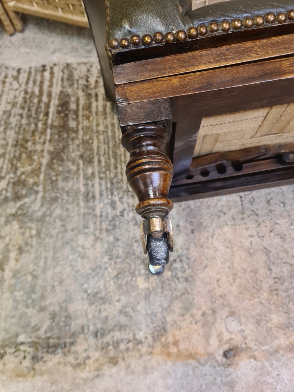 An Edwardian metamorphic gout stool crafted from dark mahogany with green leather upholstery, brass stud detailing, and a notched ratchet adjustment mechanism. View VI