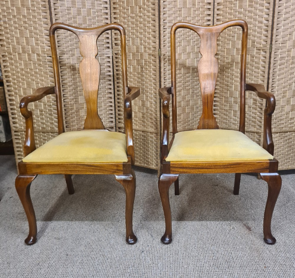 A pair of 1920s Queen Anne style walnut armchairs featuring vase-shaped splat backs, crook arms, cabriole legs with pad feet, and yellow velvet upholstered seats.