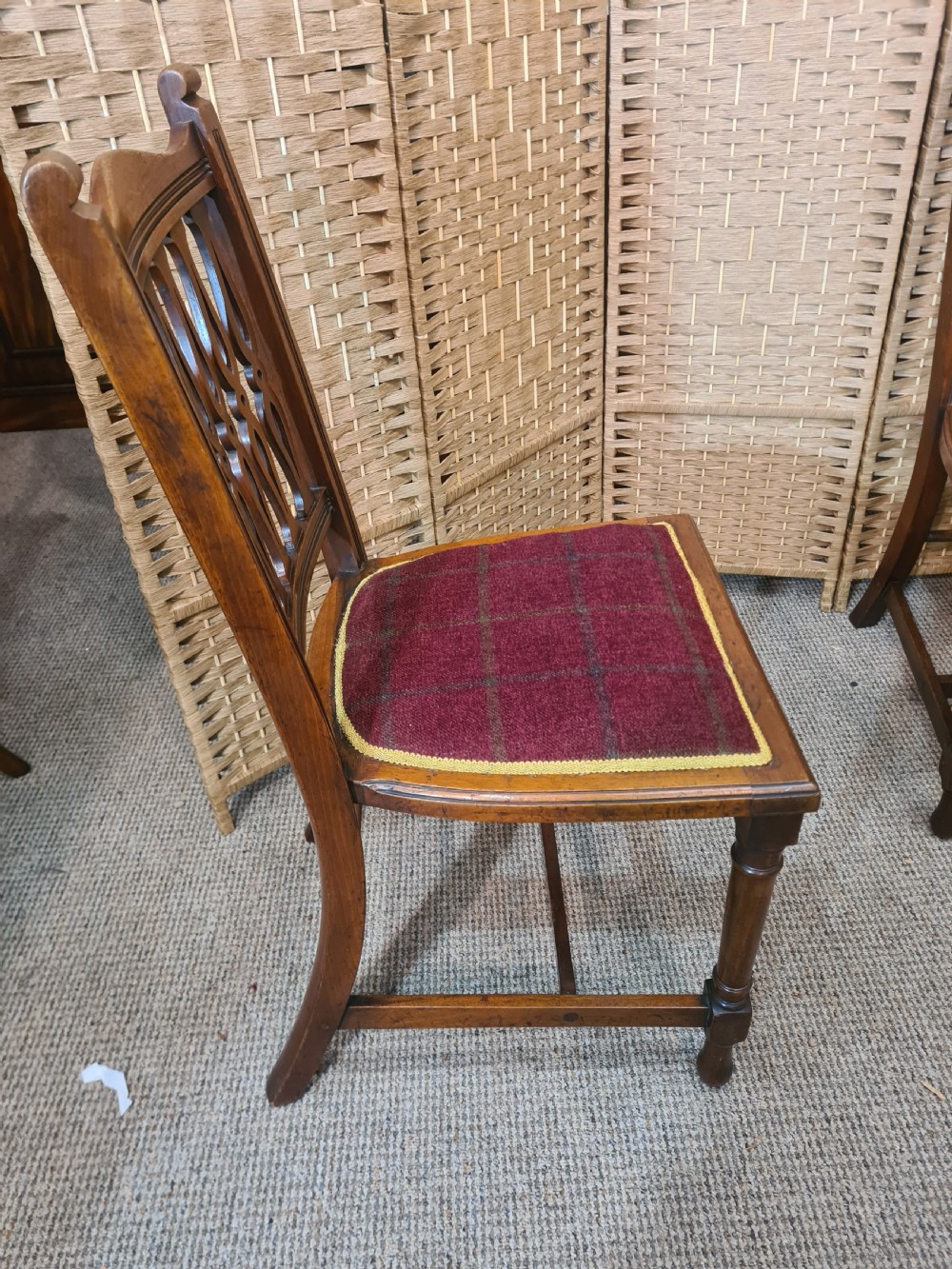 Set of six walnut Arts and Crafts dining chairs featuring pierced back slats, turned front legs, and red tartan upholstered seats with yellow trim. View VI