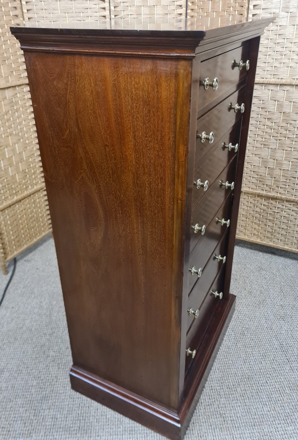 A tall, narrow late Victorian mahogany Wellington chest featuring seven drawers with satinwood stringing inlays, round brass knobs, and a side locking bar. View III