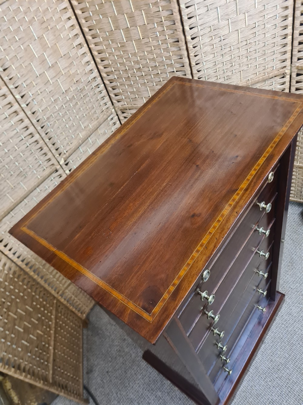 A tall, narrow late Victorian mahogany Wellington chest featuring seven drawers with satinwood stringing inlays, round brass knobs, and a side locking bar. View V