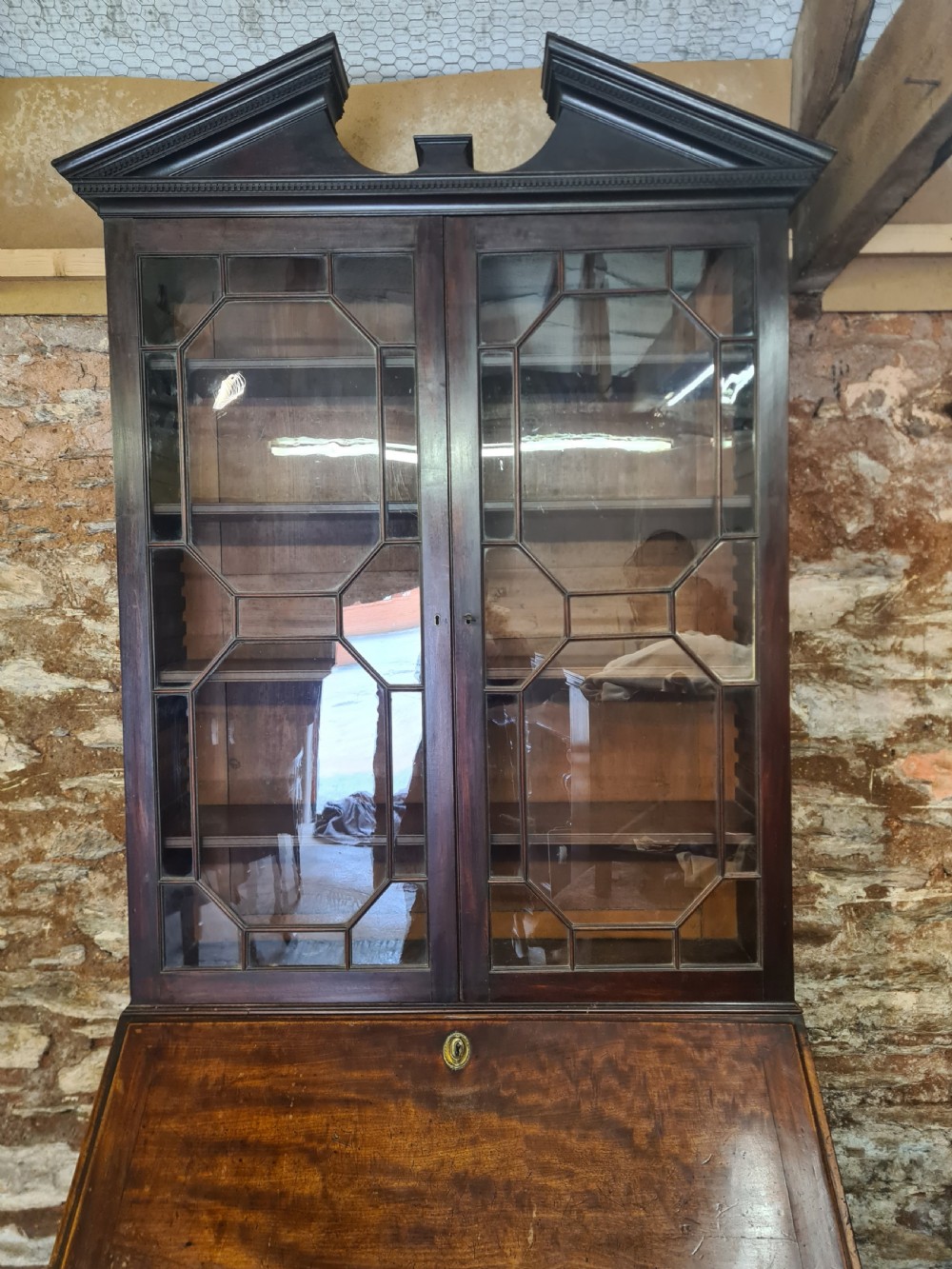 An 18th-century Georgian mahogany bureau bookcase featuring an upper astragal glazed cabinet with a pediment top above a slant-front desk and four drawers. View II