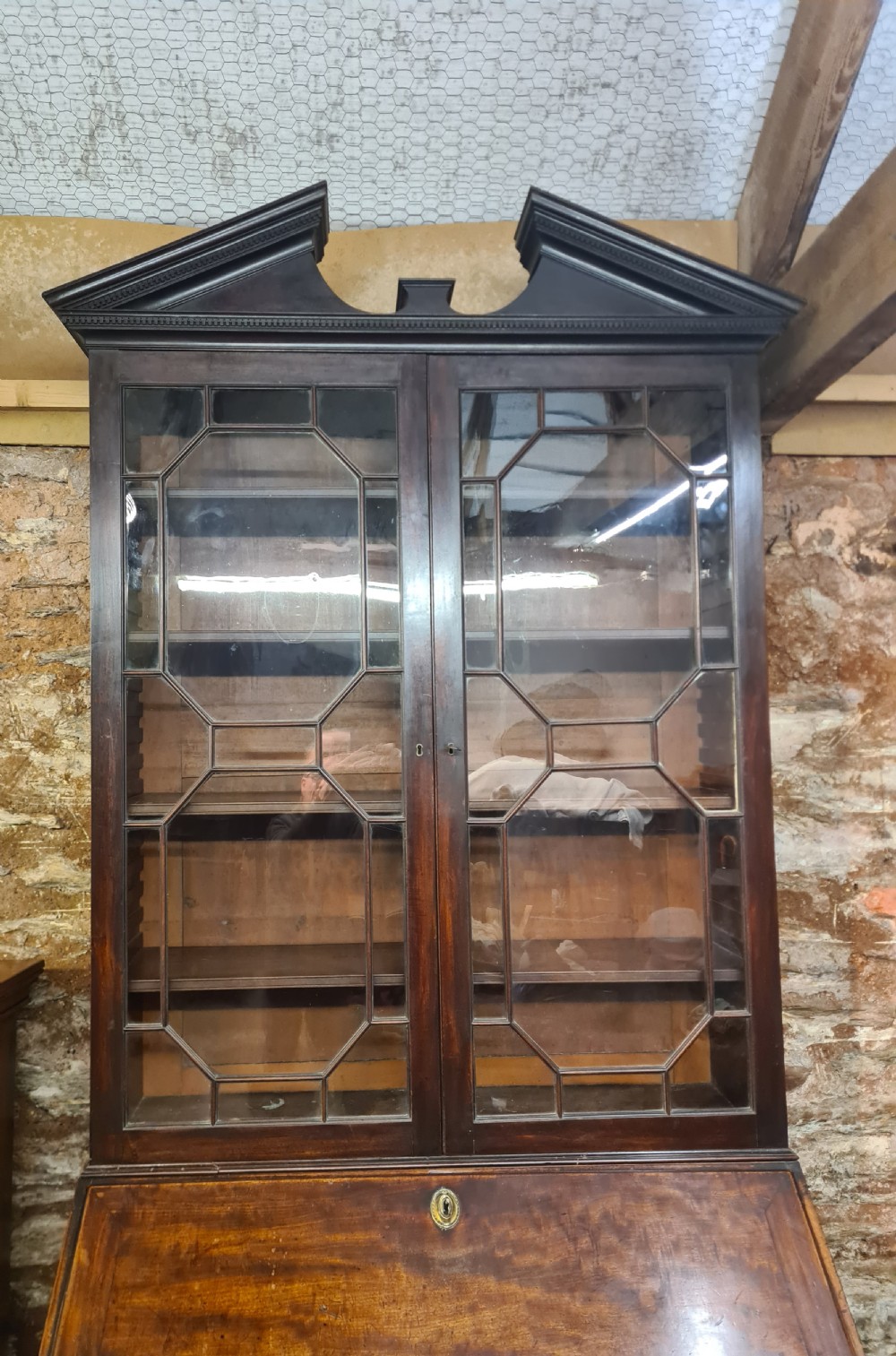 An 18th-century Georgian mahogany bureau bookcase featuring an upper astragal glazed cabinet with a pediment top above a slant-front desk and four drawers. View V