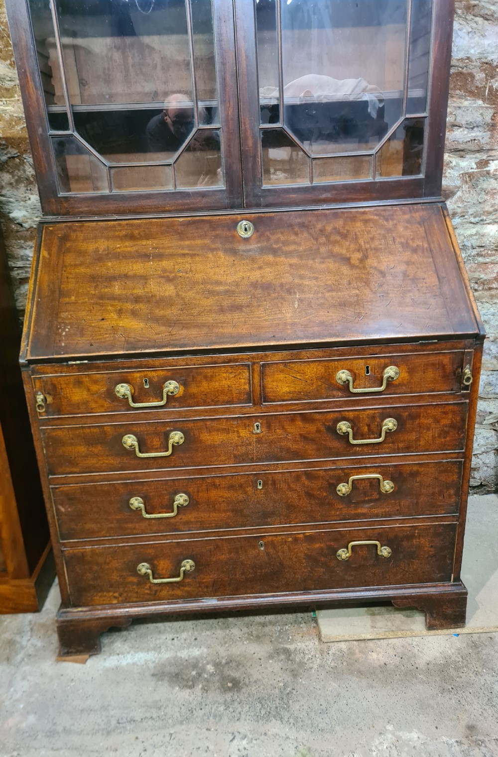 An 18th-century Georgian mahogany bureau bookcase featuring an upper astragal glazed cabinet with a pediment top above a slant-front desk and four drawers. View VI