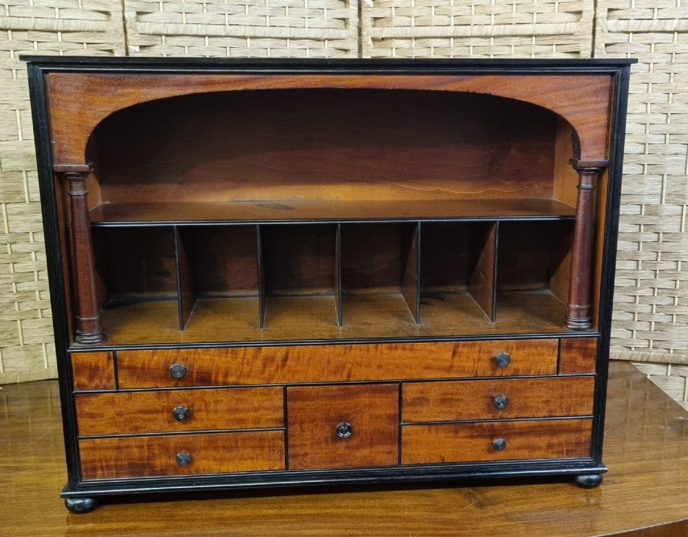 A nineteenth-century mahogany tabletop stationery cabinet featuring an open upper compartment with pigeonholes and turned side columns above six small drawers with dark turned knobs.