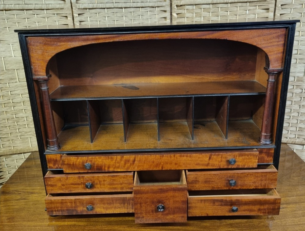 A nineteenth-century mahogany tabletop stationery cabinet featuring an open upper compartment with pigeonholes and turned side columns above six small drawers with dark turned knobs. View II