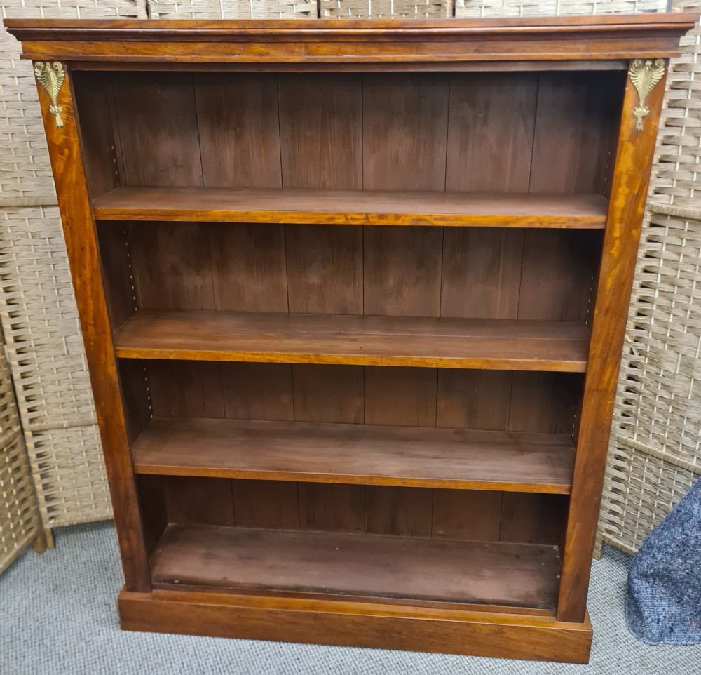 A nineteenth-century mahogany open bookcase featuring four tier shelves, a solid plinth base, and decorative brass mounts at the upper corners.