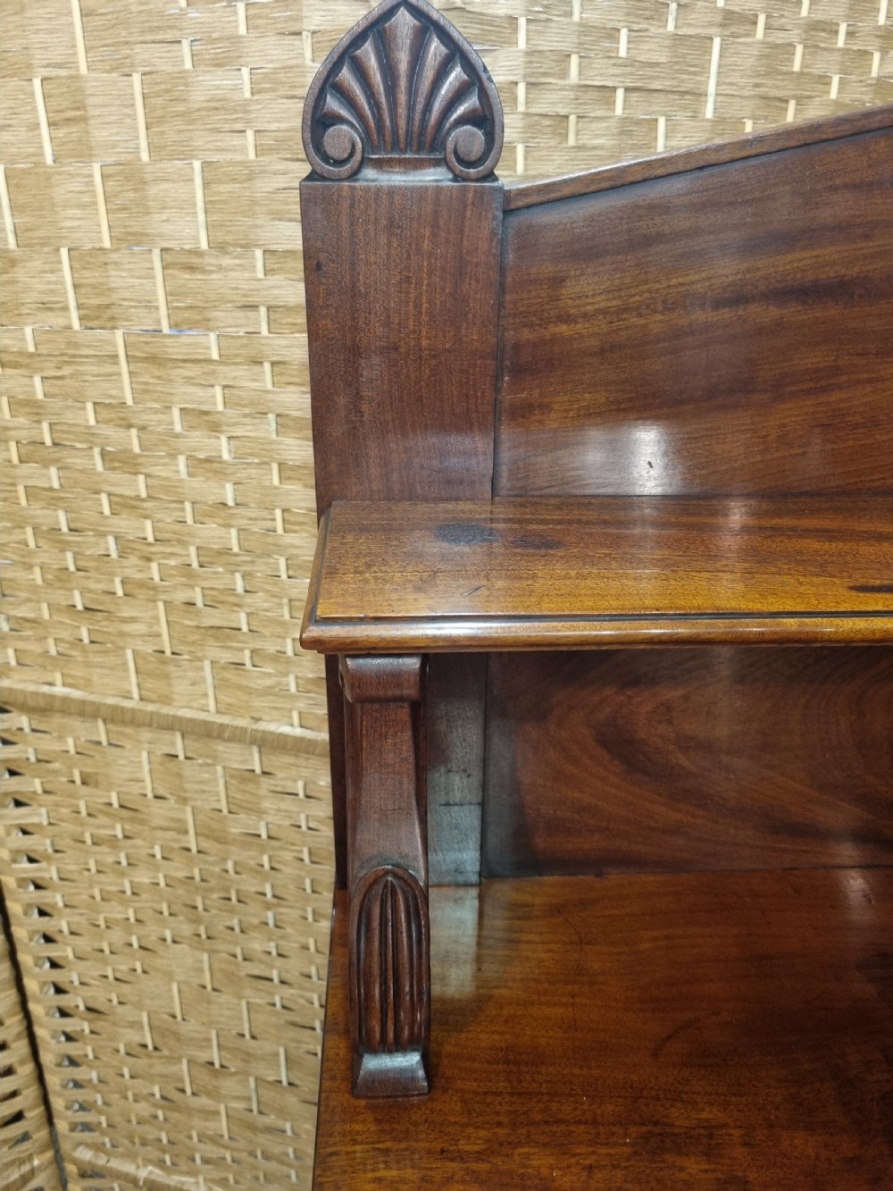 An early nineteenth-century flame mahogany chiffonier featuring a carved cresting backboard with a single shelf over a two-door cabinet flanked by turned columns. View IX
