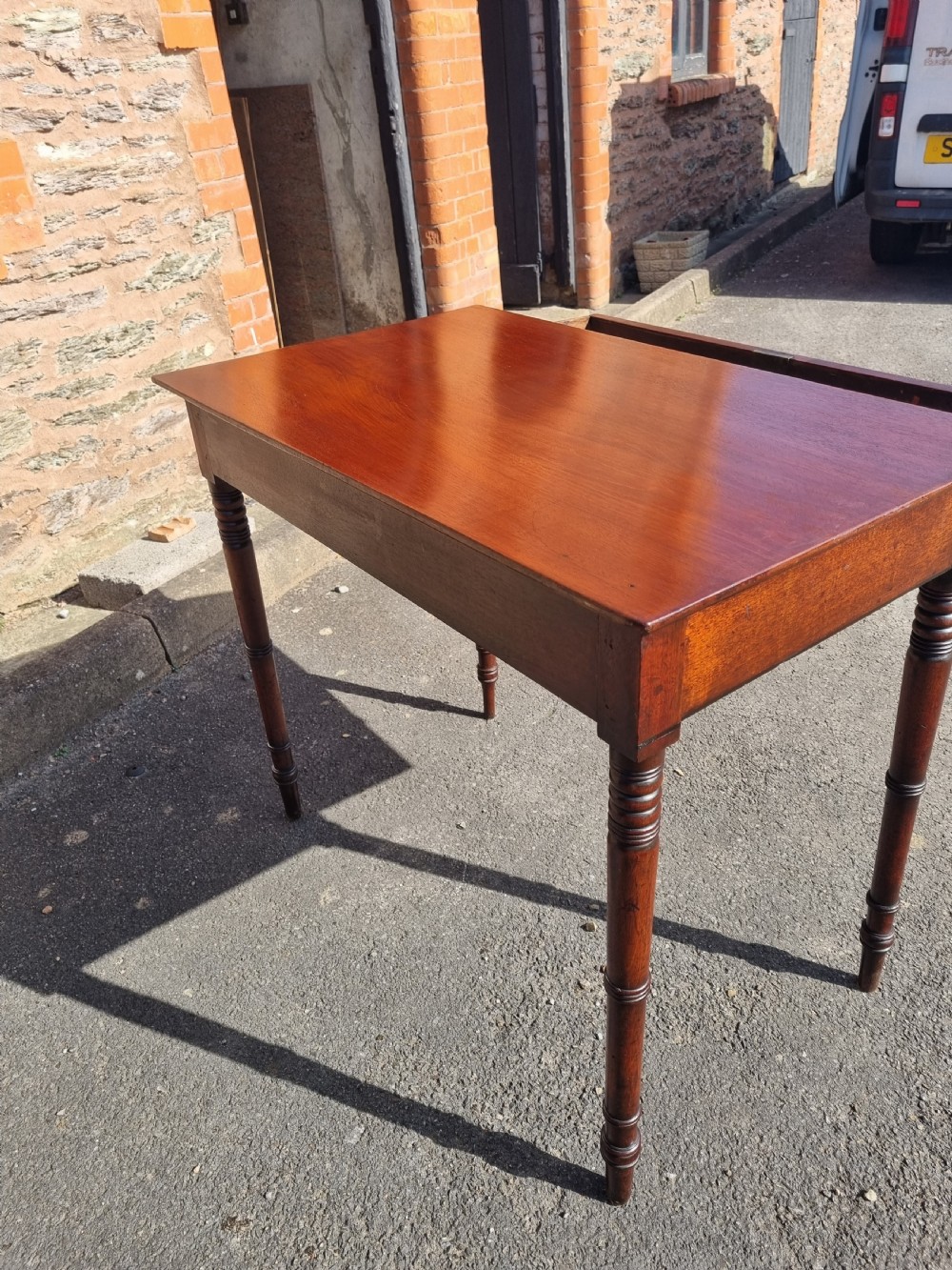 A Georgian mahogany writing table featuring a rectangular top, a single wide frieze drawer with brass ring handles, and four ring-turned legs. View III