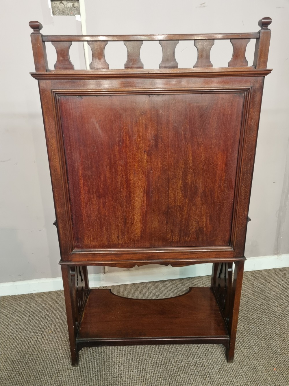 An Arts and Crafts mahogany bureau cabinet featuring a carved fall front slope, glazed upper cupboard doors, brass handles, and a lower shelf. View IX