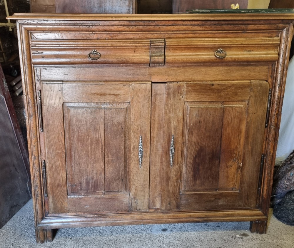 An early nineteenth-century French provincial warm brown oak cupboard with two drawers above two fielded panel doors and steel hardware.