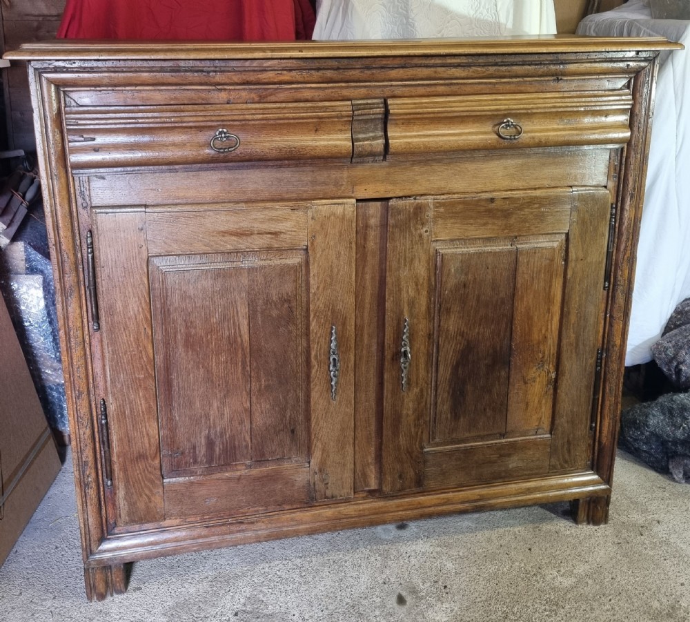 An early nineteenth-century French provincial warm brown oak cupboard with two drawers above two fielded panel doors and steel hardware. View II