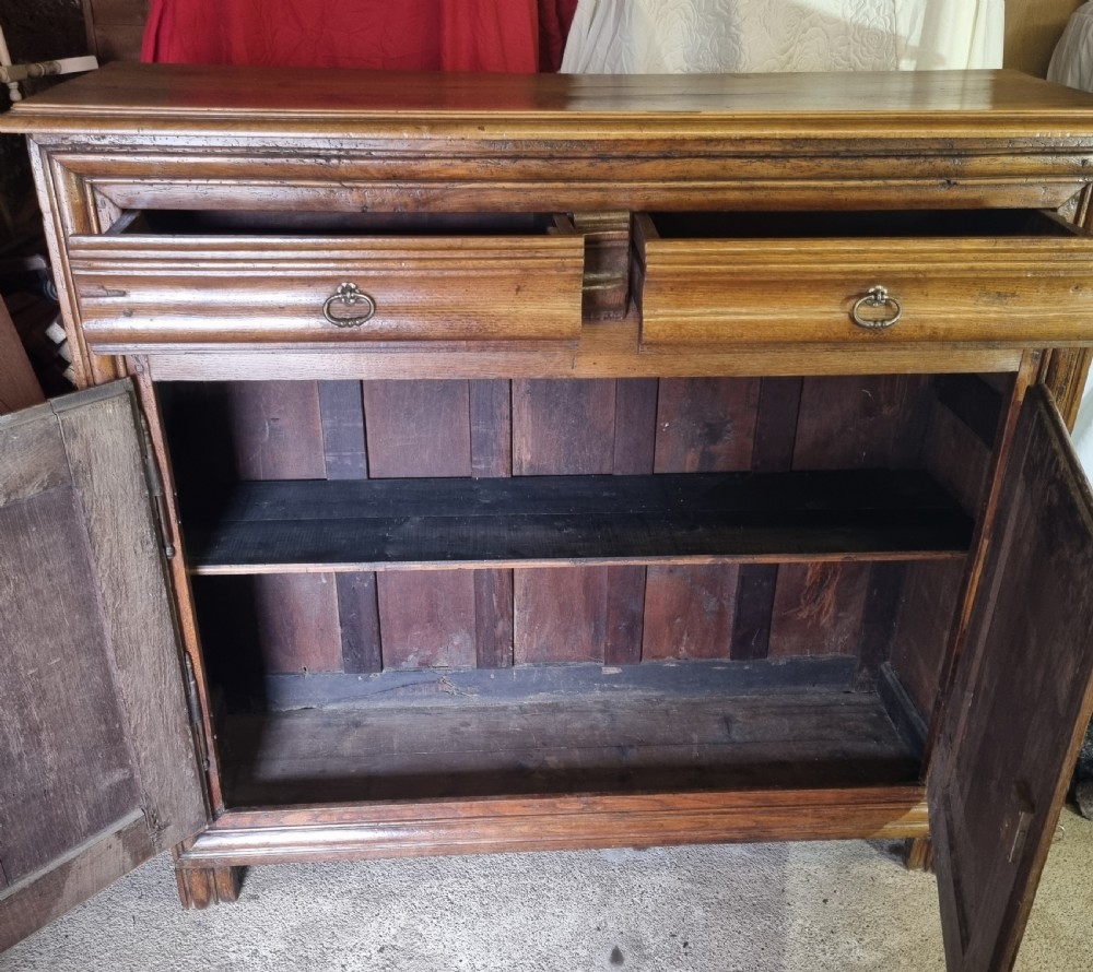 An early nineteenth-century French provincial warm brown oak cupboard with two drawers above two fielded panel doors and steel hardware. View III