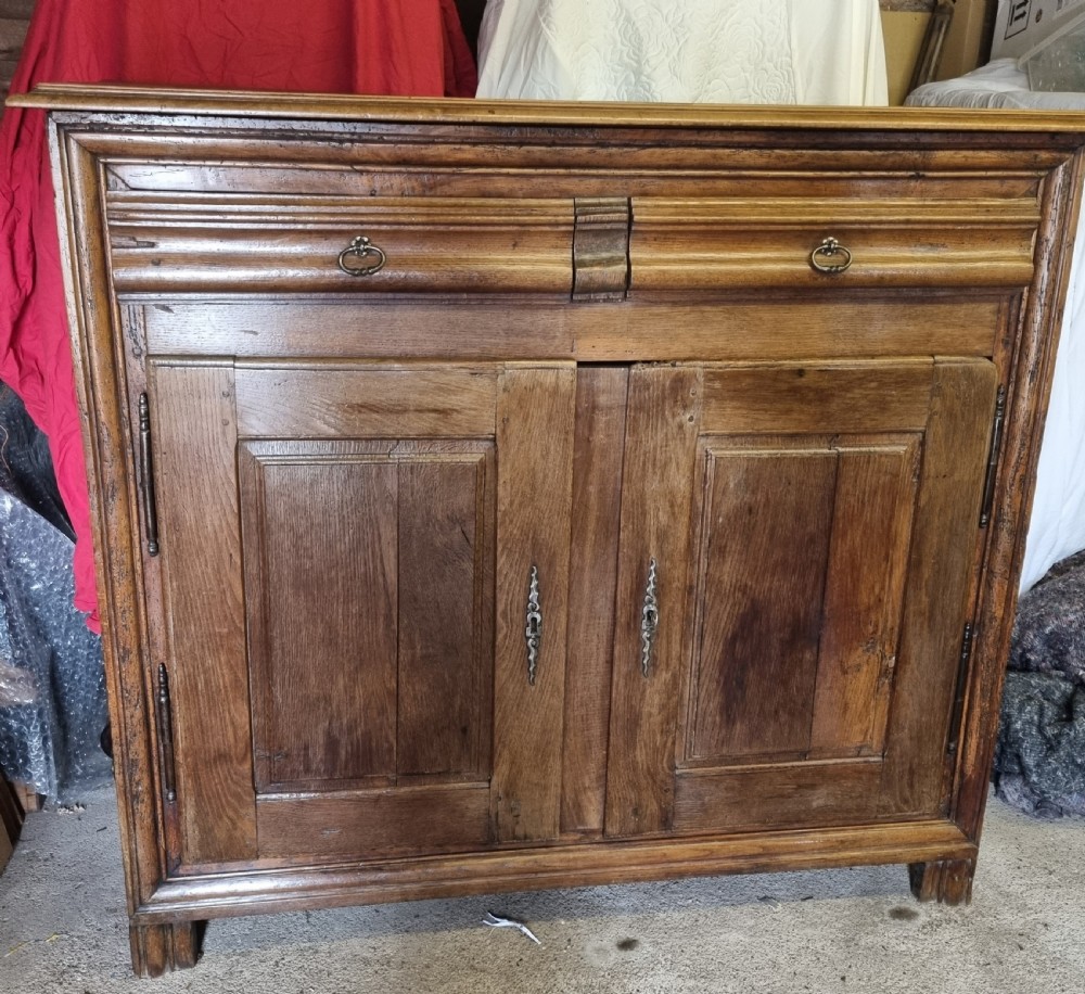 An early nineteenth-century French provincial warm brown oak cupboard with two drawers above two fielded panel doors and steel hardware. View IV