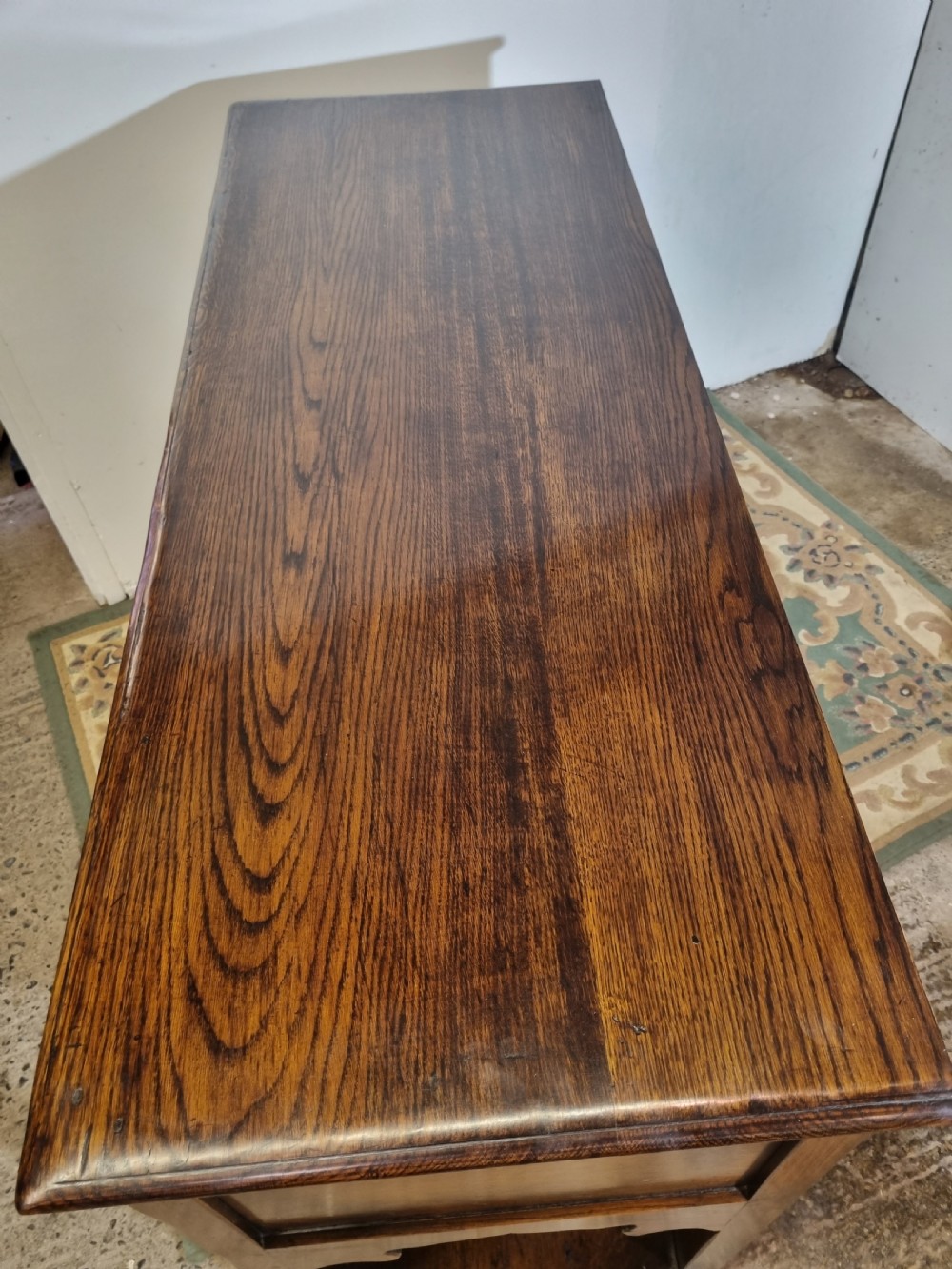 A dark oak Georgian-style dresser base featuring multiple drawers with brass handles, a scalloped apron, and an open lower potboard shelf. View III