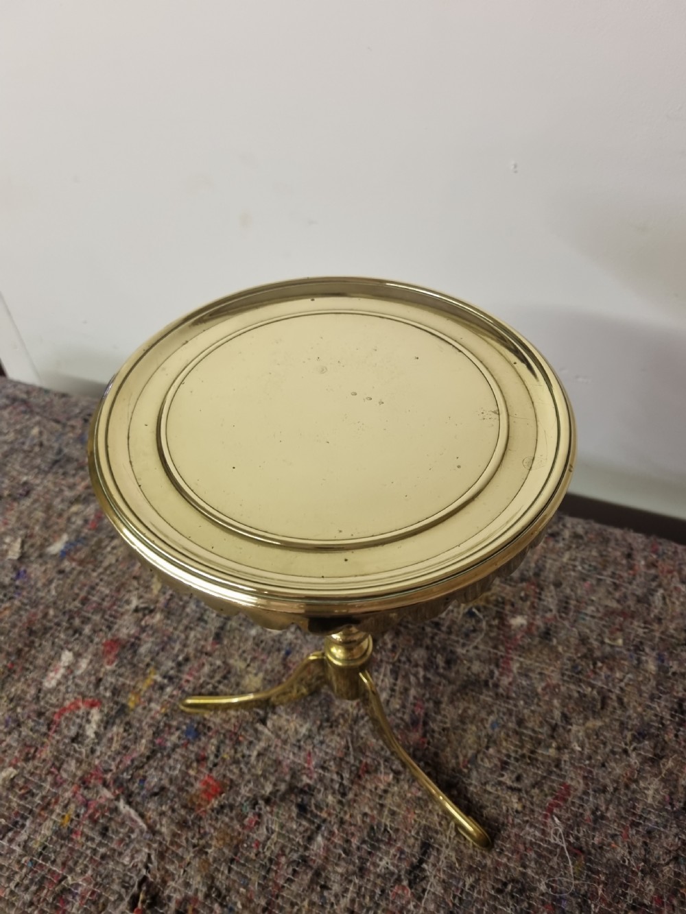 A Georgian cast brass kettle stand featuring a circular top with a scalloped rim, a turned baluster stem, and a tripod base. View II