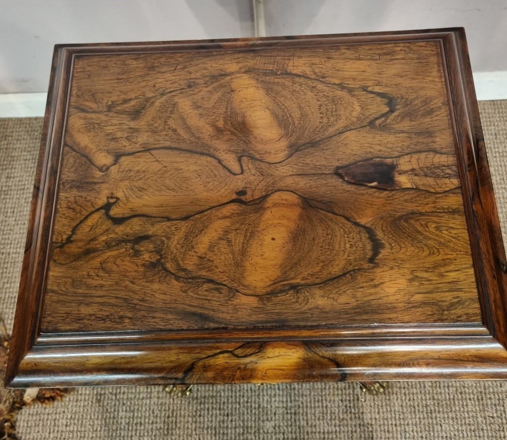 A Regency rosewood teapoy featuring a hinged sarcophagus chest supported by a tapered column and quadform base with brass lion paw feet. View VI