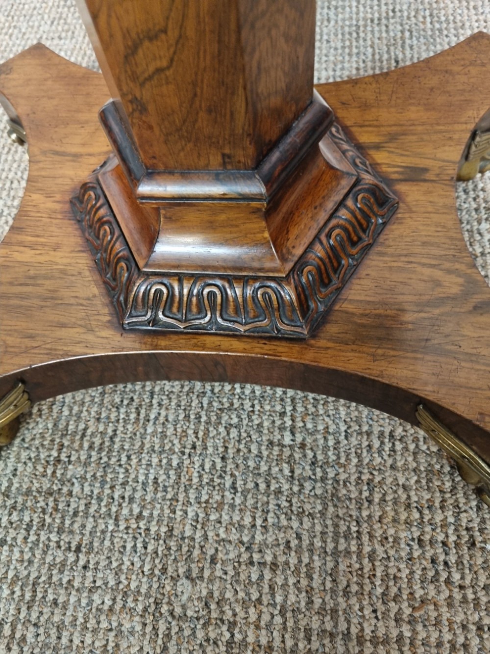 A Regency rosewood teapoy featuring a hinged sarcophagus chest supported by a tapered column and quadform base with brass lion paw feet. View VII