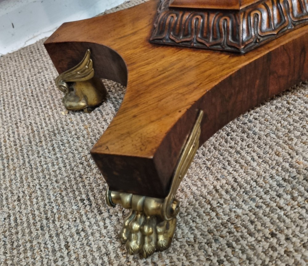A Regency rosewood teapoy featuring a hinged sarcophagus chest supported by a tapered column and quadform base with brass lion paw feet. View IX