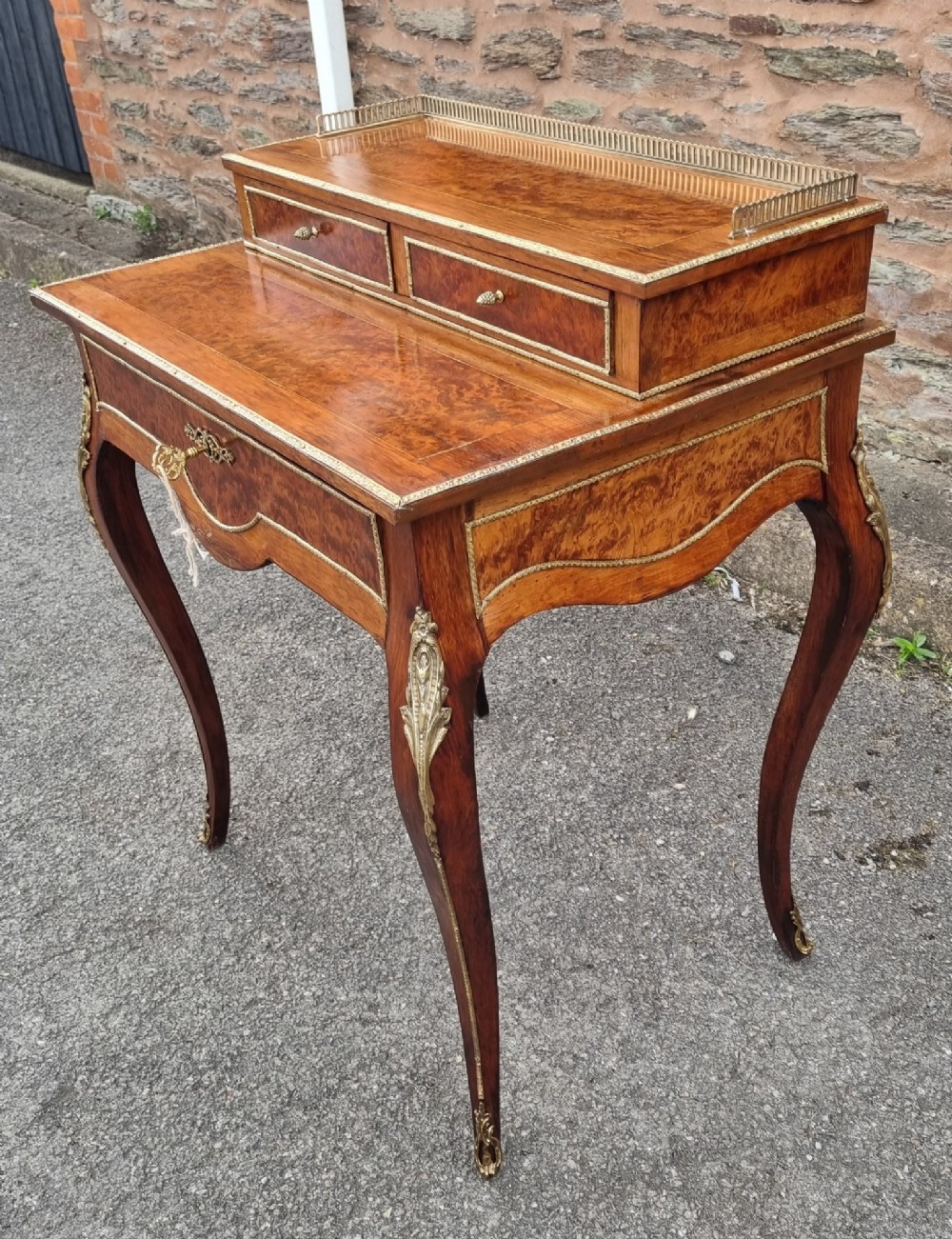 A nineteenth-century rosewood and amboyna veneer bonheur du jour desk featuring cabriole legs, gilt-metal mounts, and a brass gallery rail on the raised upper shelf. View II