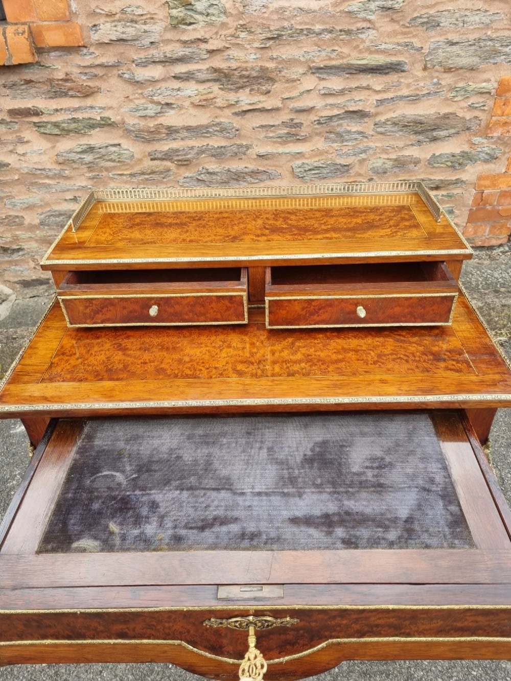 A nineteenth-century rosewood and amboyna veneer bonheur du jour desk featuring cabriole legs, gilt-metal mounts, and a brass gallery rail on the raised upper shelf. View VI