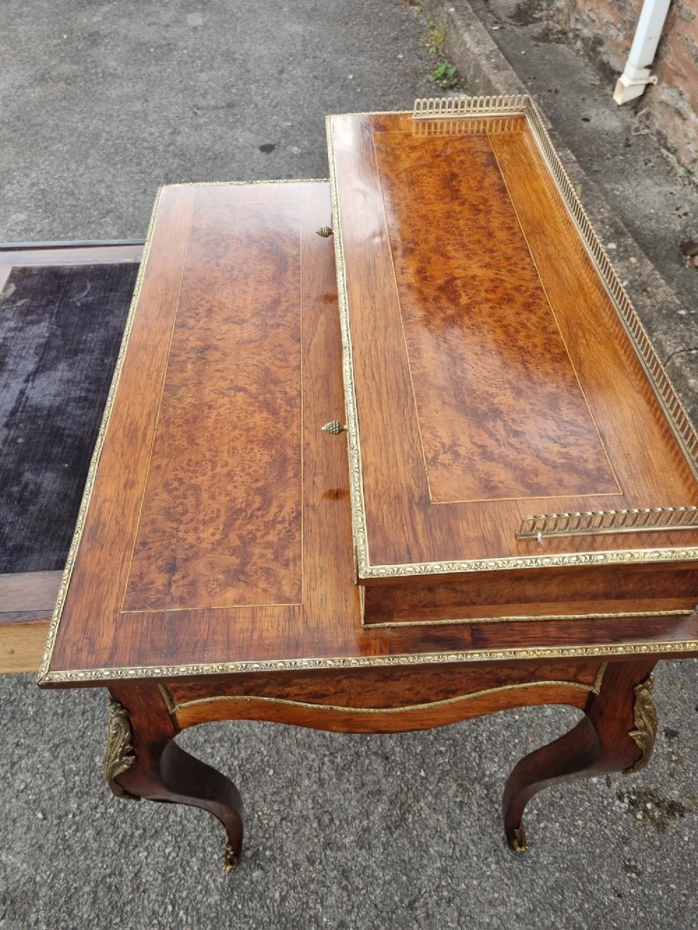 A nineteenth-century rosewood and amboyna veneer bonheur du jour desk featuring cabriole legs, gilt-metal mounts, and a brass gallery rail on the raised upper shelf. View X