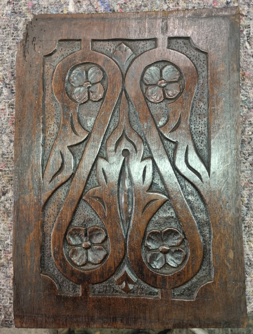 A set of four dark oak carved wooden panels featuring relief floral and foliate motifs with textured stippled backgrounds. View II