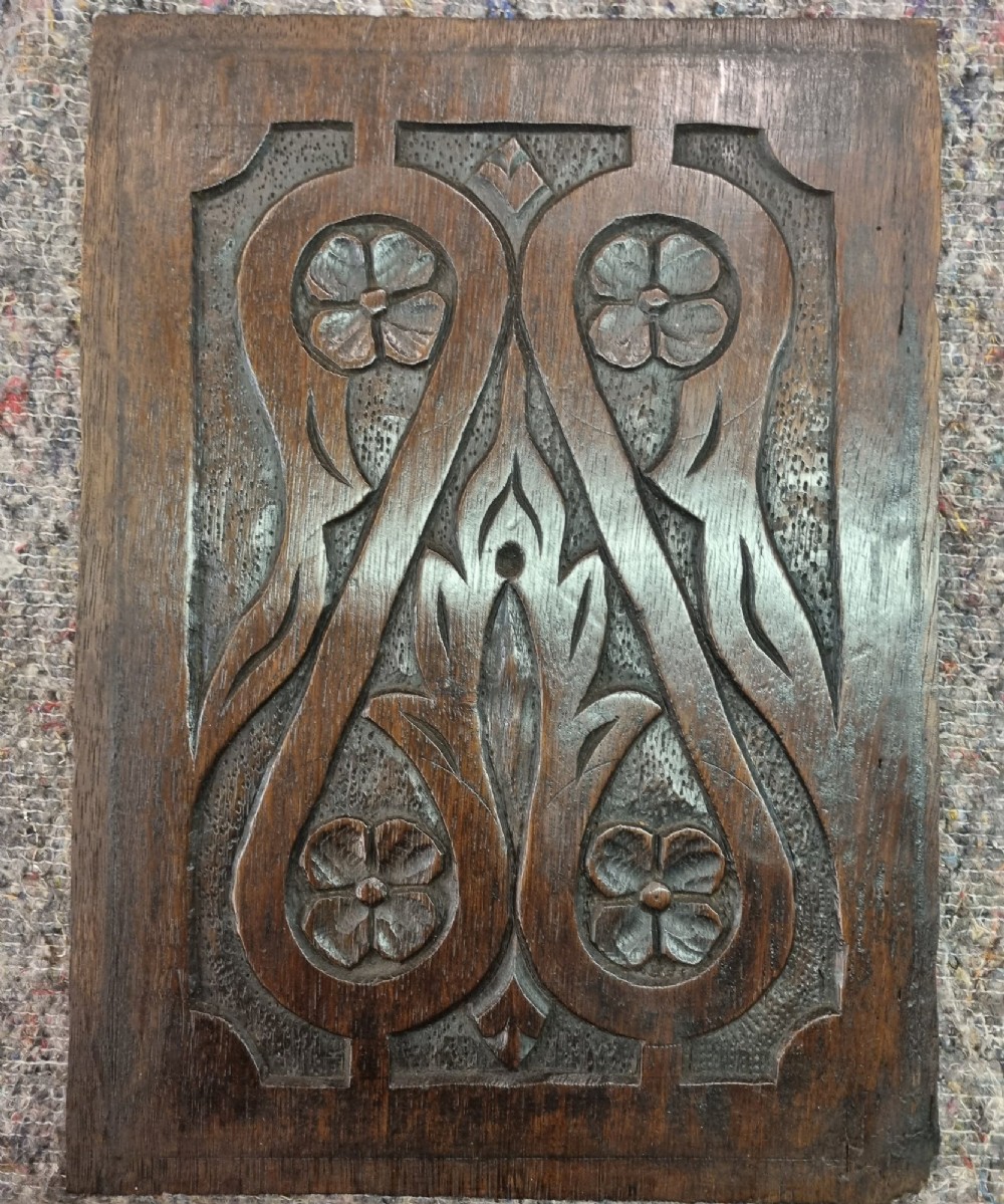 A set of four dark oak carved wooden panels featuring relief floral and foliate motifs with textured stippled backgrounds. View III