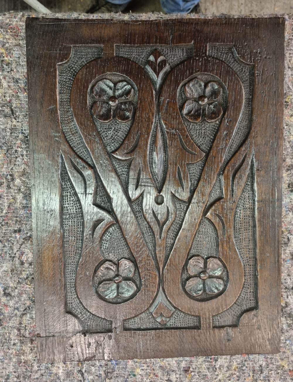 A set of four dark oak carved wooden panels featuring relief floral and foliate motifs with textured stippled backgrounds. View IV