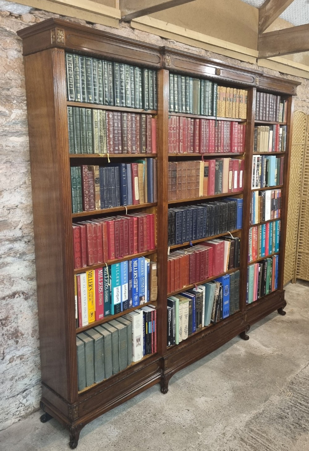 An Edwardian walnut breakfront open bookcase with three fitted sections, carved patera details, and fluted pilasters. View III