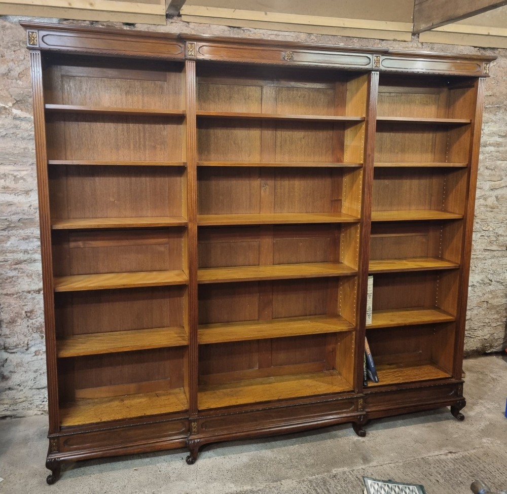 An Edwardian walnut breakfront open bookcase with three fitted sections, carved patera details, and fluted pilasters. View IV