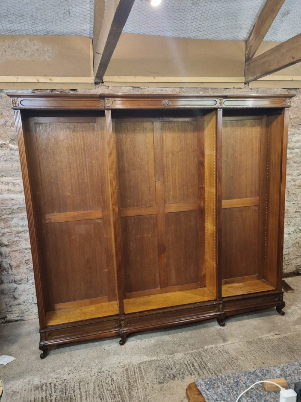 An Edwardian walnut breakfront open bookcase with three fitted sections, carved patera details, and fluted pilasters. View V