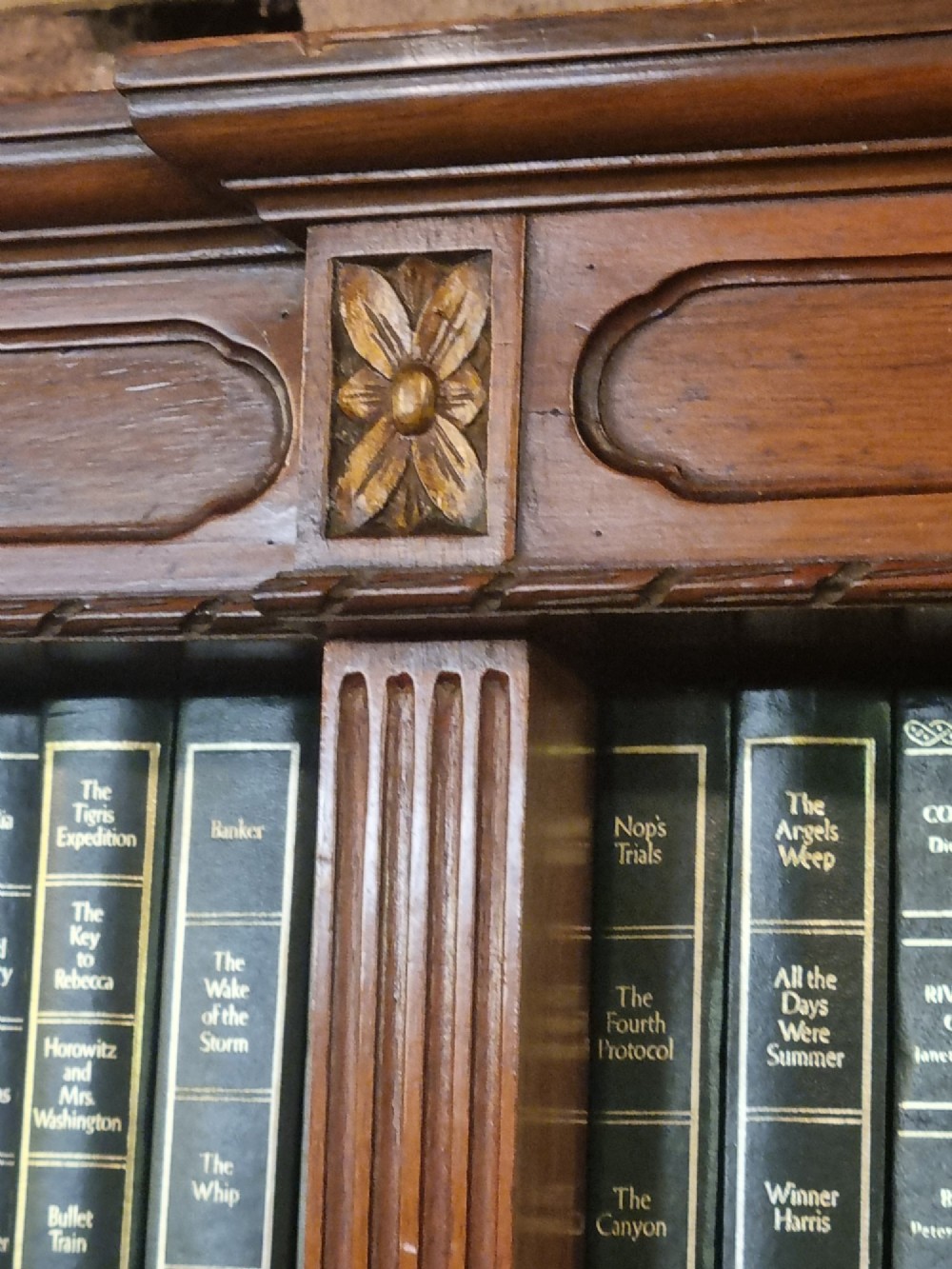 An Edwardian walnut breakfront open bookcase with three fitted sections, carved patera details, and fluted pilasters. View VII