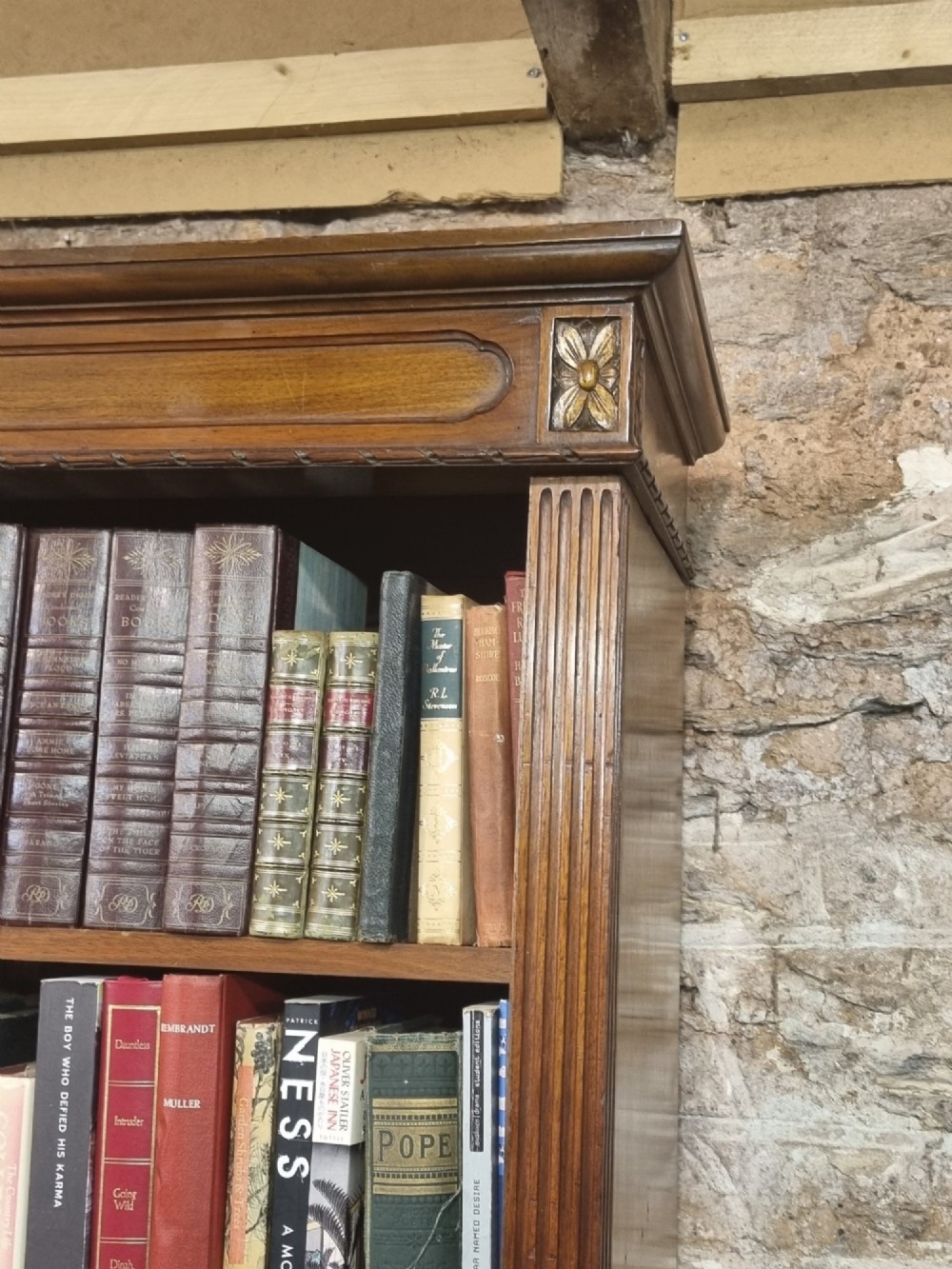 An Edwardian walnut breakfront open bookcase with three fitted sections, carved patera details, and fluted pilasters. View X