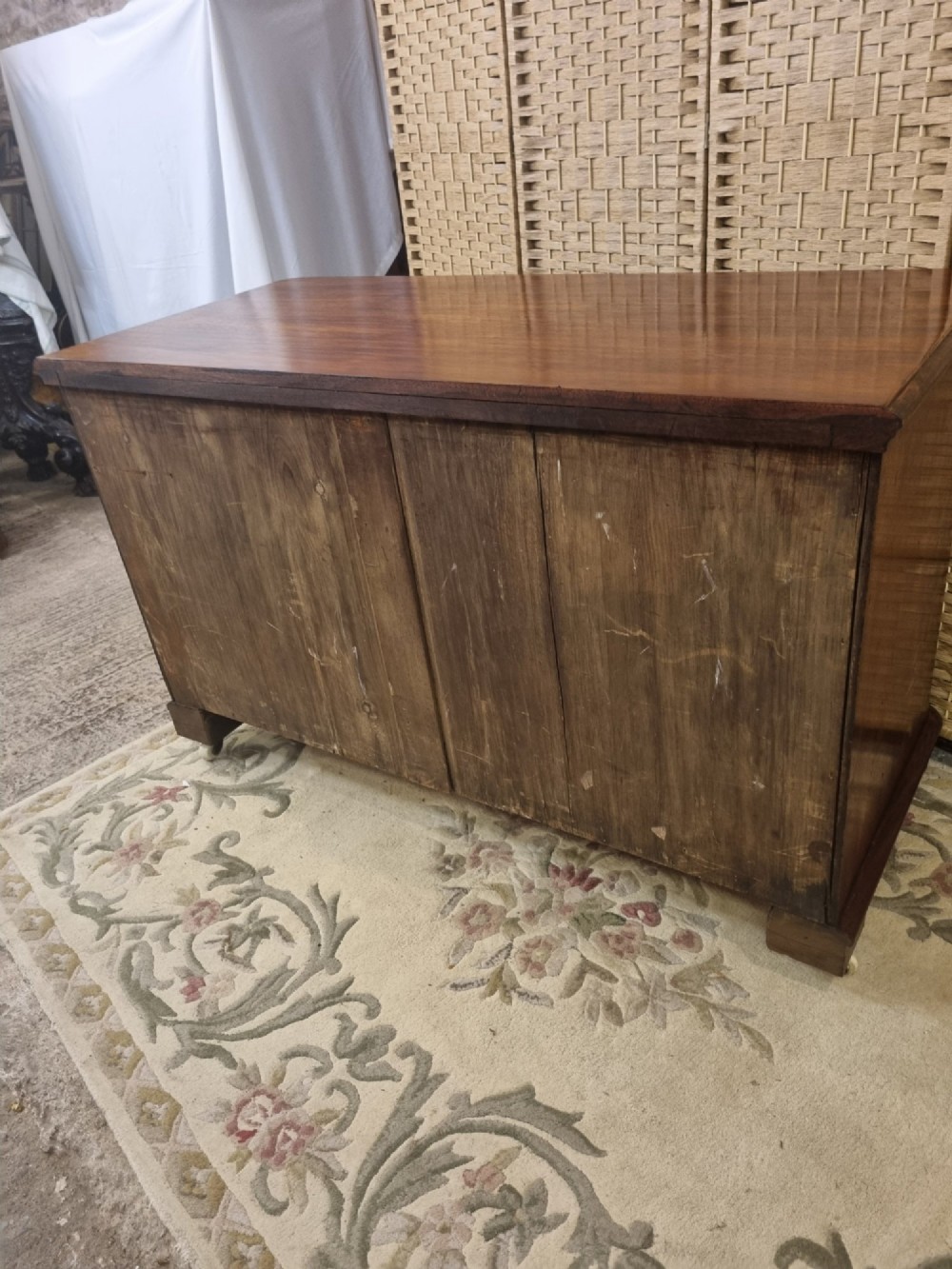 A nineteenth-century flame mahogany chest of drawers featuring two short over two long drawers with turned wooden knobs, rounded moulding, and short turned feet with castors. View III