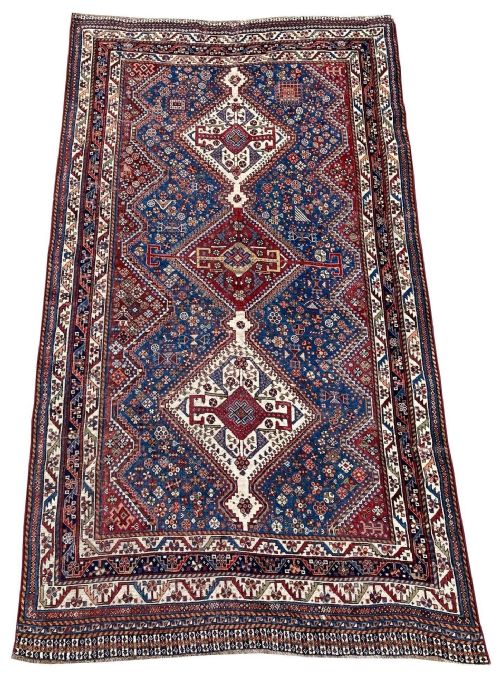 fig 1. An antique Persian Qashqai wool rug displaying three diamond medallions on a navy blue field filled with geometric tribal motifs and framed by a detailed multi-tiered border.