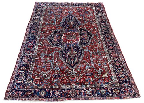 fig 1. An antique hand-knotted Heriz wool carpet with a large geometric central medallion on a terracotta red field surrounded by navy blue borders.
