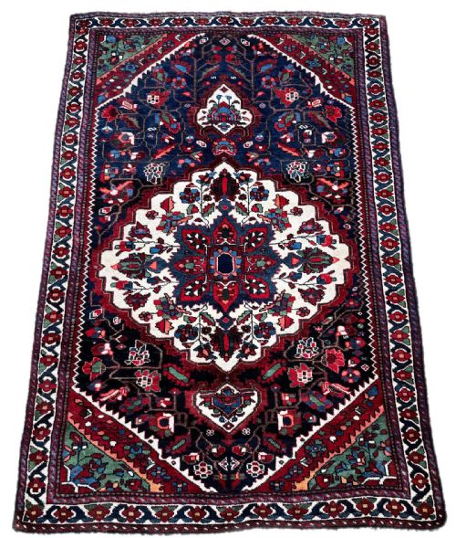 fig 1. An antique handwoven Luri rug featuring horizontal polychrome stripes in terracotta, green, blue, and yellow with small geometric motifs.