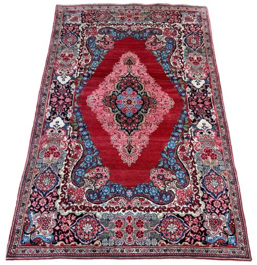 fig 1. Hand-knotted antique Persian Sarouk wool rug featuring a large central floral medallion on a rich red ground with elaborate decorative borders.